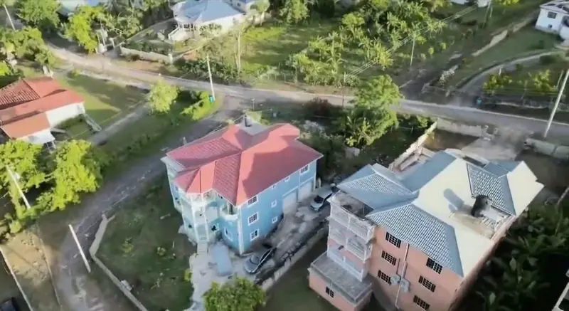 Aerial view of the house beside the lane, with cars in the driveway