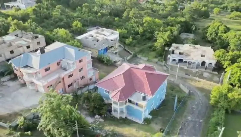 Aerial view of the house among neighbouring homes and green hillside