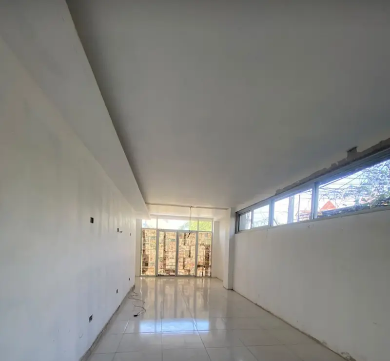 Empty ground-floor unit: a long tiled room with high windows and a glass front