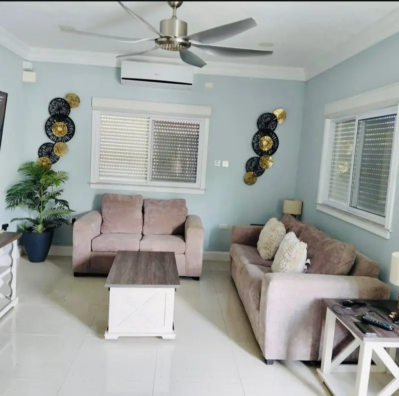 Furnished living room in pale blue with two sofas and a ceiling fan