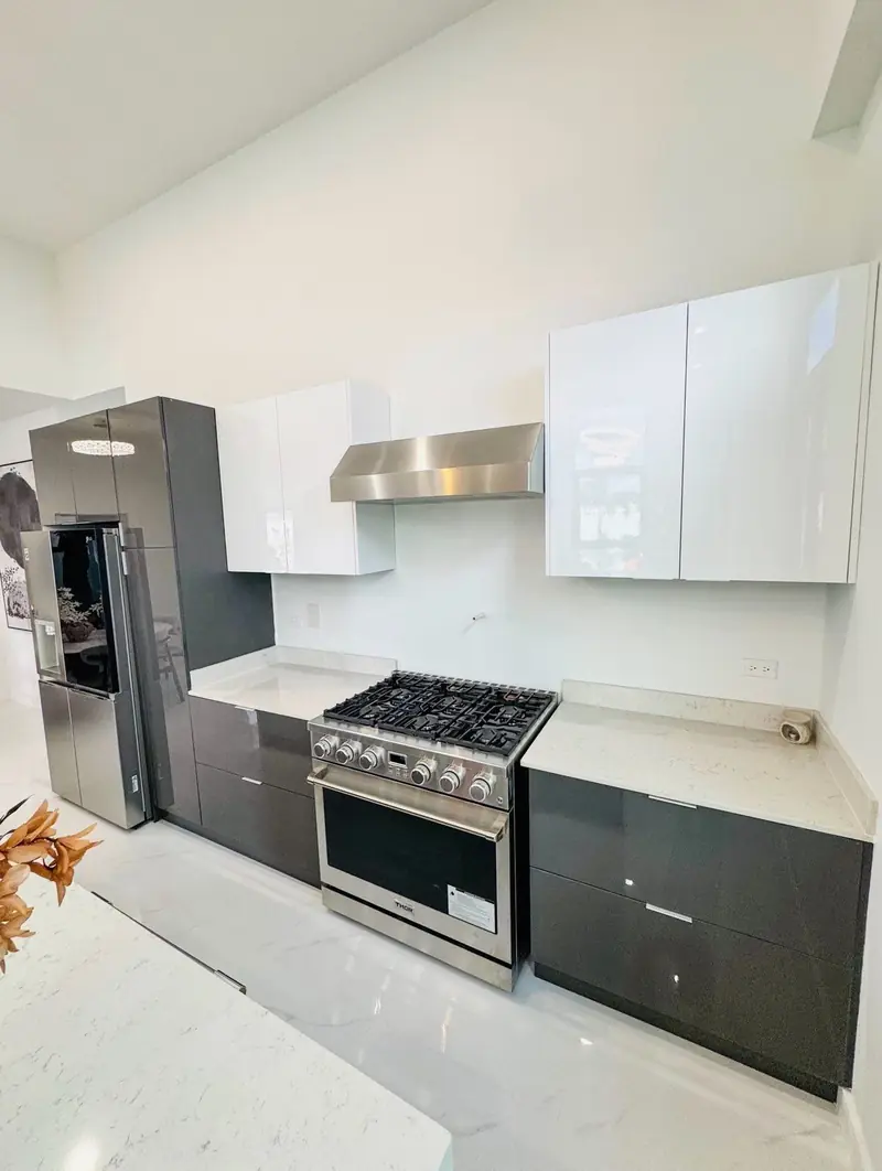 Kitchen with dark cabinets, white stone counters, gas range and steel fridge